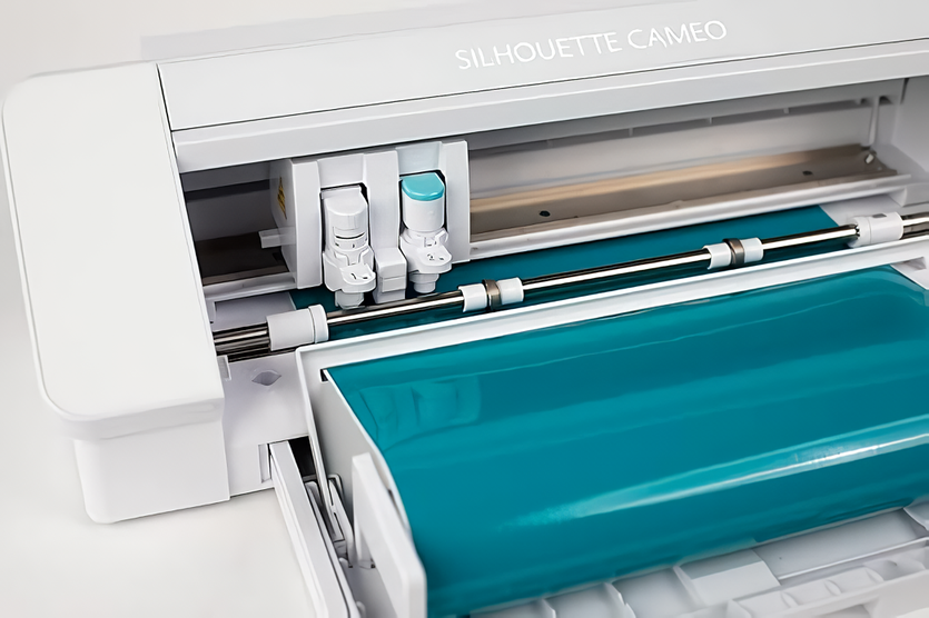 Close‑up plotter Silhouette Cameo 4 cortando vinil turquesa con alimentador de rollo | Tienda Revenato